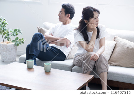 一對50多歲的夫婦坐在沙發上，無聊地打架，一副關係不好的冷漠夫妻的形象。 116407515