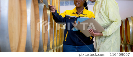 Winemaker team checking and examining producing wine at winery in factory. 116409007