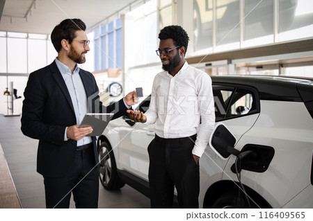 Dealer sells electric SUV to businessman in car dealership Dealer sells electric SUV to businessman in car dealership 116409565