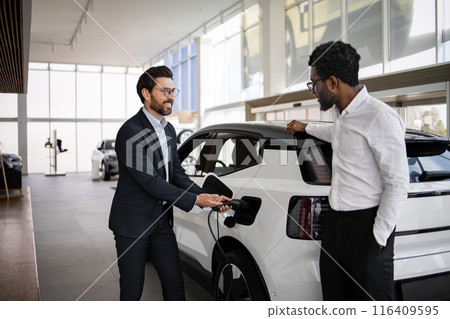 Dealer sells electric SUV to businessman in car dealership Dealer sells electric SUV to businessman in car dealership 116409595