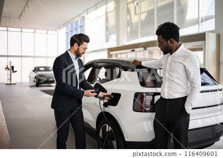 Dealer selling electric SUV to businessman in modern showroom 116409601