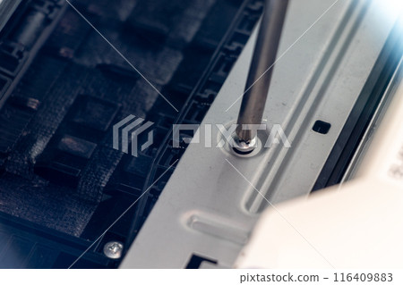Turning the screws on a machine part with a screwdriver 116409883