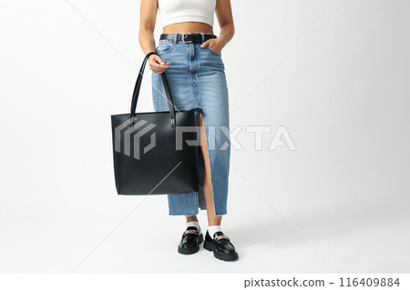 Woman in denim skirt with leather black bag on white background Woman in denim skirt with leather black bag on white background 116409884