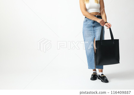 Woman in denim skirt with leather black bag on white background, space for text Woman in denim skirt with leather black bag on white background, space for text 116409887