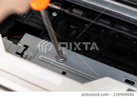 Turning the screws on a machine part with a screwdriver Turning the screws on a machine part with a screwdriver 116409888