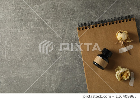 Dried white rose buds, notepad and bottle of ink on gray background, space for text Dried white rose buds, notepad and bottle of ink on gray background, space for text 116409965