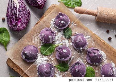 Purple dumplings on kitchen board and cabbage on light background, top view Purple dumplings on kitchen board and cabbage on light background, top view 116409971