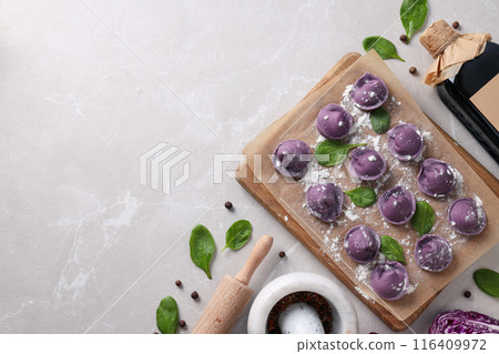 Purple dumplings on kitchen board, cabbage and spices on light background, space for text Purple dumplings on kitchen board, cabbage and spices on light background, space for text 116409972