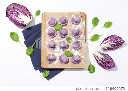 Purple dumplings on kitchen board, basil and cabbage on white background, top view Purple dumplings on kitchen board, basil and cabbage on white background, top view 116409973