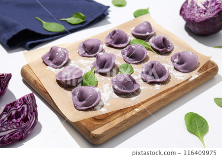 Purple dumplings on kitchen board, basil and cabbage on white background Purple dumplings on kitchen board, basil and cabbage on white background 116409975