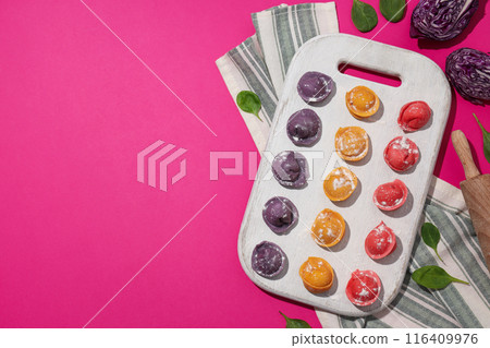 Colored dumplings on kitchen board and towel on pink background, space for text Colored dumplings on kitchen board and towel on pink background, space for text 116409976
