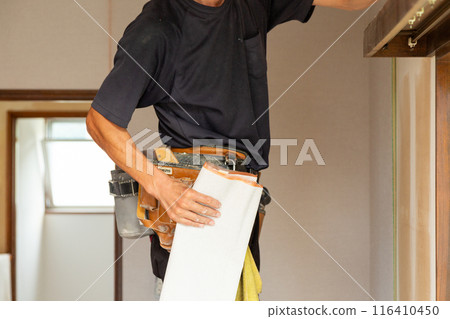 A craftsman applying wallpaper to a used house 116410450