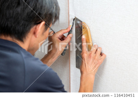 A craftsman applying wallpaper to a used house 116410451