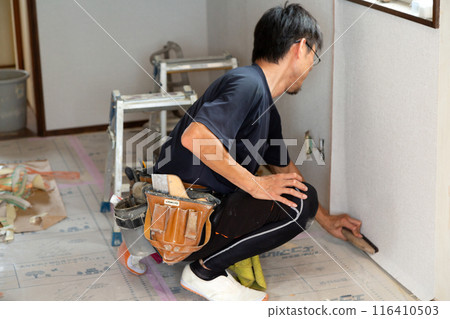 A craftsman applying wallpaper to a used house 116410503