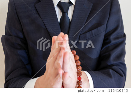 一個男人手裡拿著念珠,雙手合十 一個男人手裡拿著念珠,雙手合十 116410543
