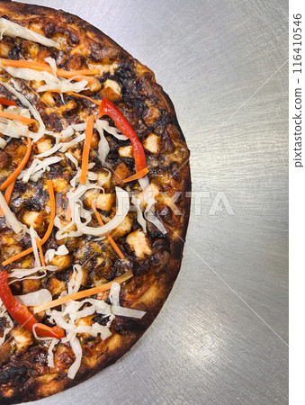 Special black garlic pizza sauce with pickels in half on stainless steel table. Special black garlic pizza sauce with pickels in half on stainless steel table. 116410546