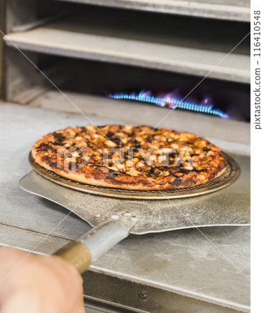 Chef takes pizza from oven in traditional restaurant. Chef takes pizza from oven in traditional restaurant. 116410548