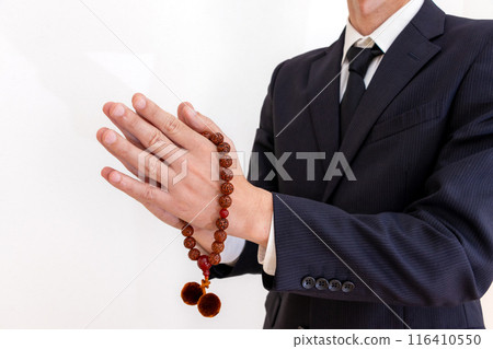 A man holding prayer beads in his hands and clasping his hands together A man holding prayer beads in his hands and clasping his hands together 116410550
