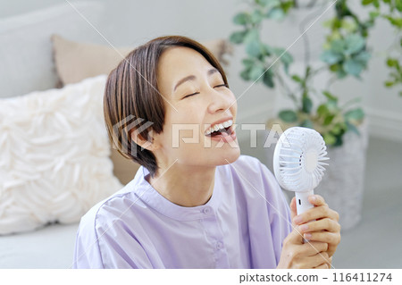 一位女士在客廳使用便攜式風扇 116411274