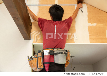 A craftsman applying wallpaper to a used house 116412593