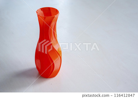 Object in the form of a vase of red color printed on a 3D printer. Three-dimensional model printed on a 3D printer from molten plastic of red color. Concept 3D Printing. FDM 3D Printing technology Object in the form of a vase of red color printed on a 3D printer. Three-dimensional model printed on a 3D printer from molten plastic of red color. Concept 3D Printing. FDM 3D Printing technology 116412847