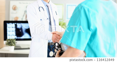 Two doctors in office shaking hands celebrating successful treatment 116412849