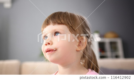 Little girl eating sweet chocolate candy with trace at her mouth 116412902