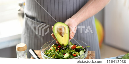 Male Hand Holding Oiled Tropical Avocado Half 116412988