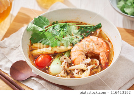 A hearty spicy soup made with glass noodles and topped with shrimp and other ingredients. 116413192