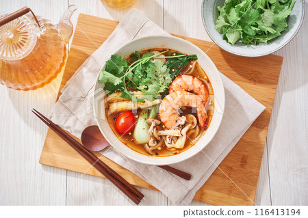 A hearty spicy soup made with glass noodles and topped with shrimp and other ingredients. 116413194