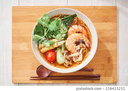 A hearty spicy soup made with glass noodles and topped with shrimp and other ingredients. 116413231