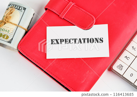 inscription Expectations word on a business card on a red notebook with dollars and a calculator lying next to it 116413685