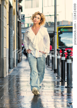 Mature woman walks in city street Mature woman walks in city street 116414099