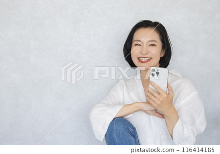 拿著智能手機的一名微笑的婦女 拿著智能手機的一名微笑的婦女 116414185