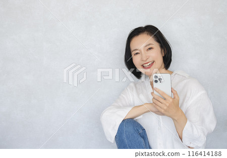 拿著智能手機的一名微笑的婦女 116414188
