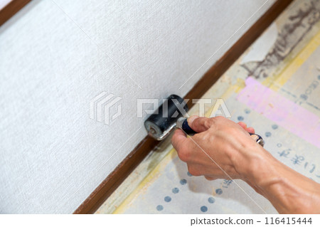 A craftsman applying wallpaper to a used house 116415444