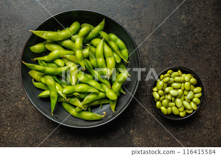 Green edamame pods. Fresh soybeans on plate on black table. Top view. Green edamame pods. Fresh soybeans on plate on black table. Top view. 116415584