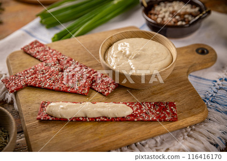 Bowl of hummus with red beetroot crackers 116416170