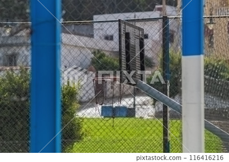 Outdoor play basketball hoop, the mesh of which is made of metal chain links. The site is fenced with a high fence, chain-link mesh, active recreation areas for young people on the city street 116416216