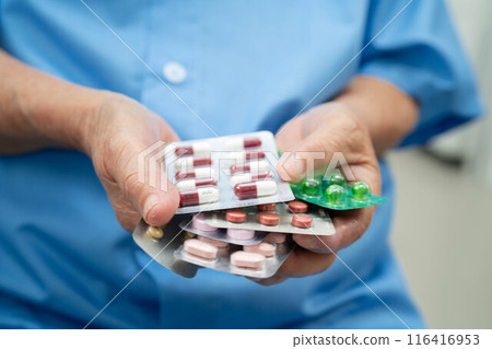 Senior Asian woman holding capsule pills drug in blister packaging for treatment infection patient in hospital. Senior Asian woman holding capsule pills drug in blister packaging for treatment infection patient in hospital. 116416953
