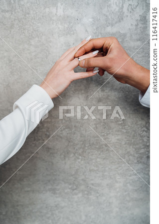 The hands of a man and a woman exchange wedding rings.  116417416