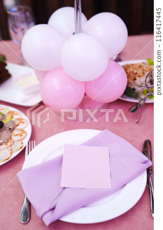 Table setting. A plate with purple napkins and a seating card.  116417445