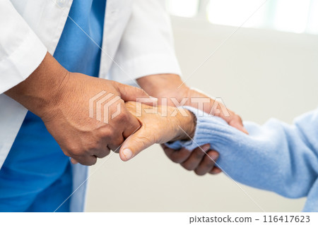 Doctor holding hand and help senior woman patient in hospital. 116417623