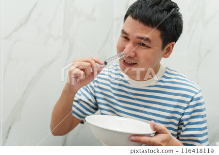 man making nasal wash with using sryinge flushing inside nose 116418119
