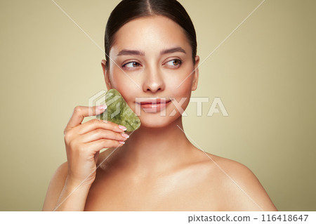 Young woman doing scrapping massage facial skin Young woman doing scrapping massage facial skin 116418647