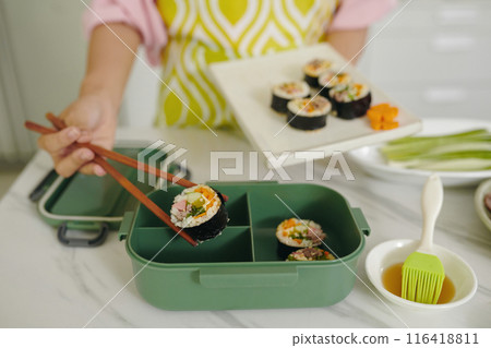 Woman Putting Kimbap In Lunchbox 116418811