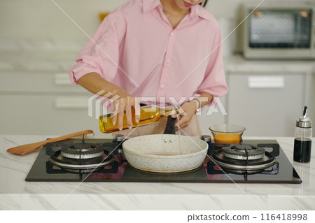 Housewife Pouring Oil On Pan 116418998