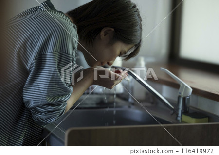 Woman drinking tap water 116419972