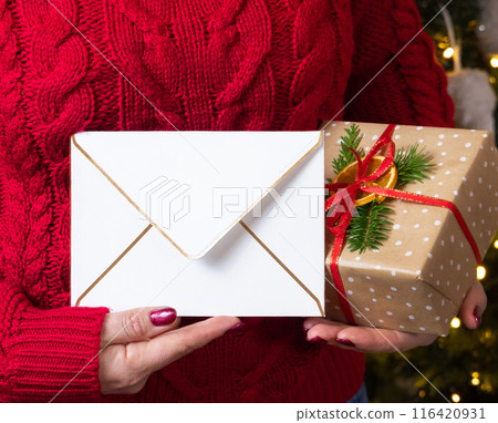 Woman in red sweater with blank envelope and present in hands, mockup 116420931