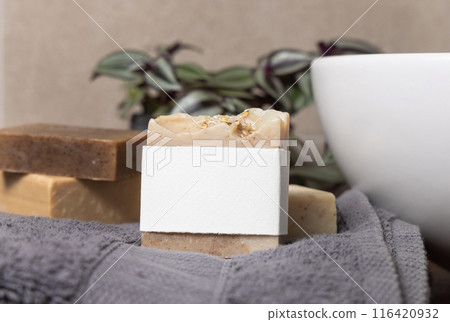 Soap bar with blank label near grey towels, plant and basin on wood in bathroom, mockup 116420932